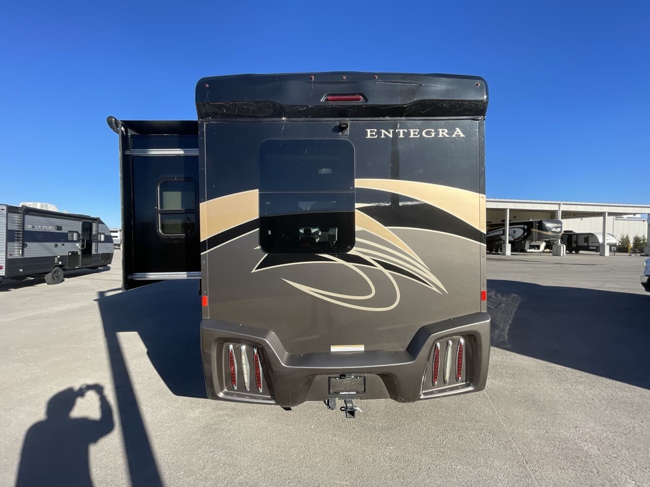 Entegra Coach QWEST 24 from the rear with the entry door open at camp